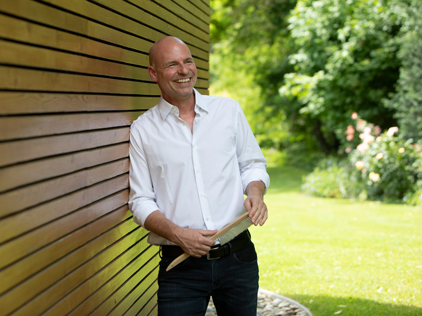 Thomas Zelenka lachend vor einer Holzwand